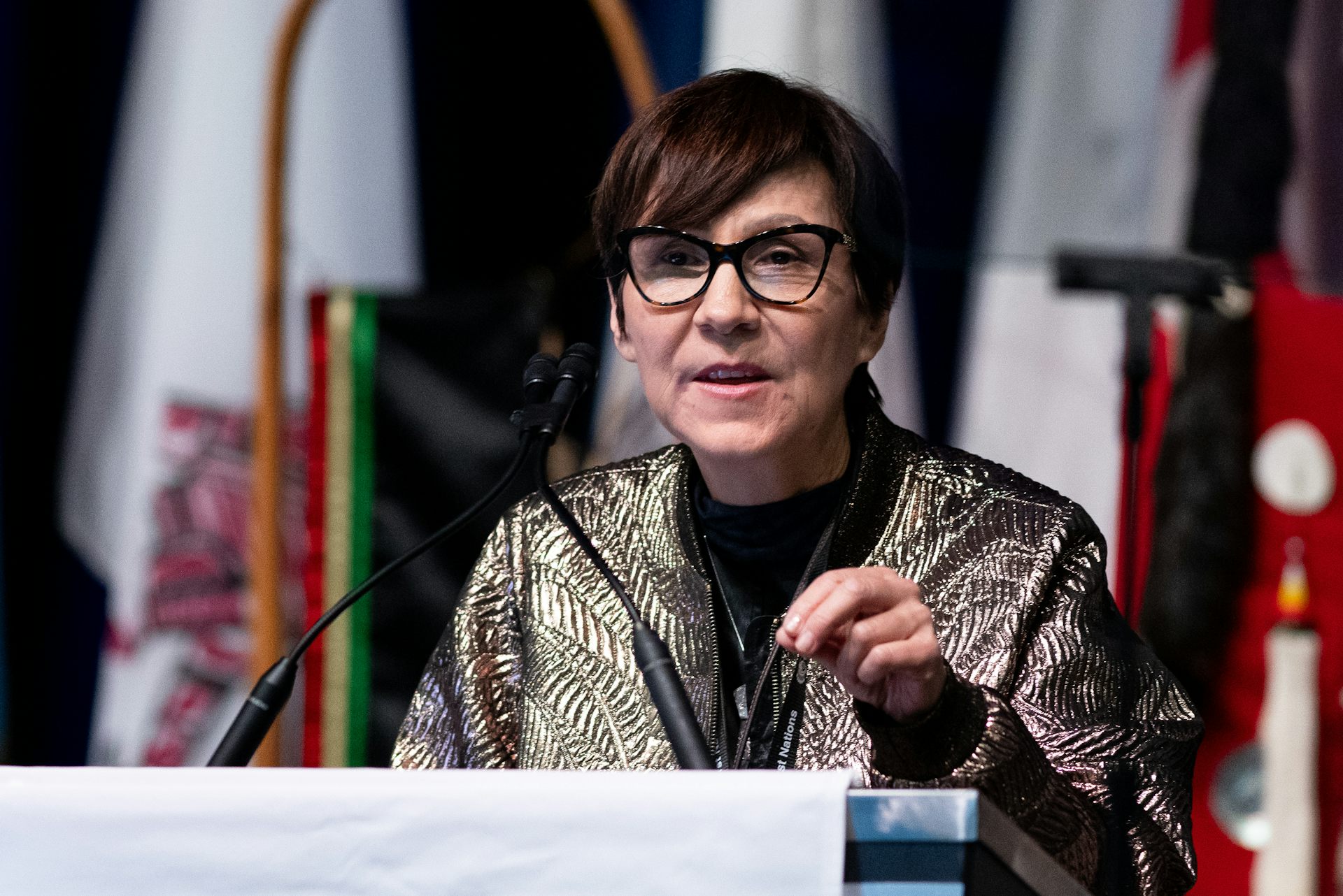 A woman with a short hairstyle speaking at a podium.