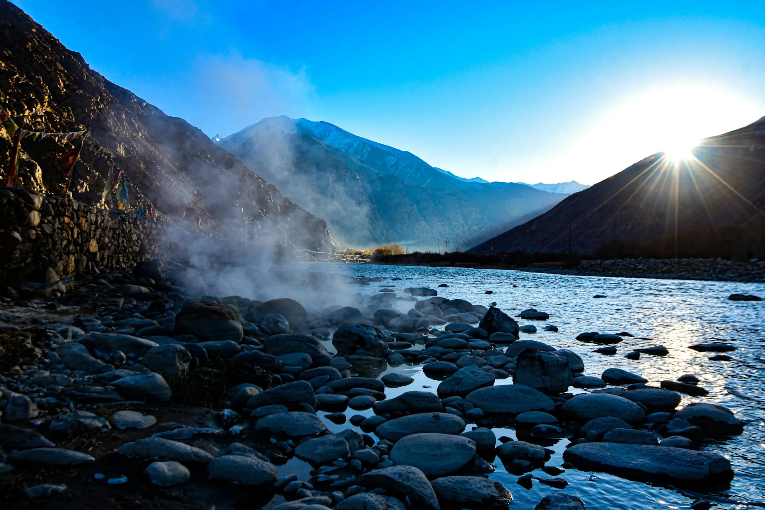 Steam rising from rocky water amid mountains