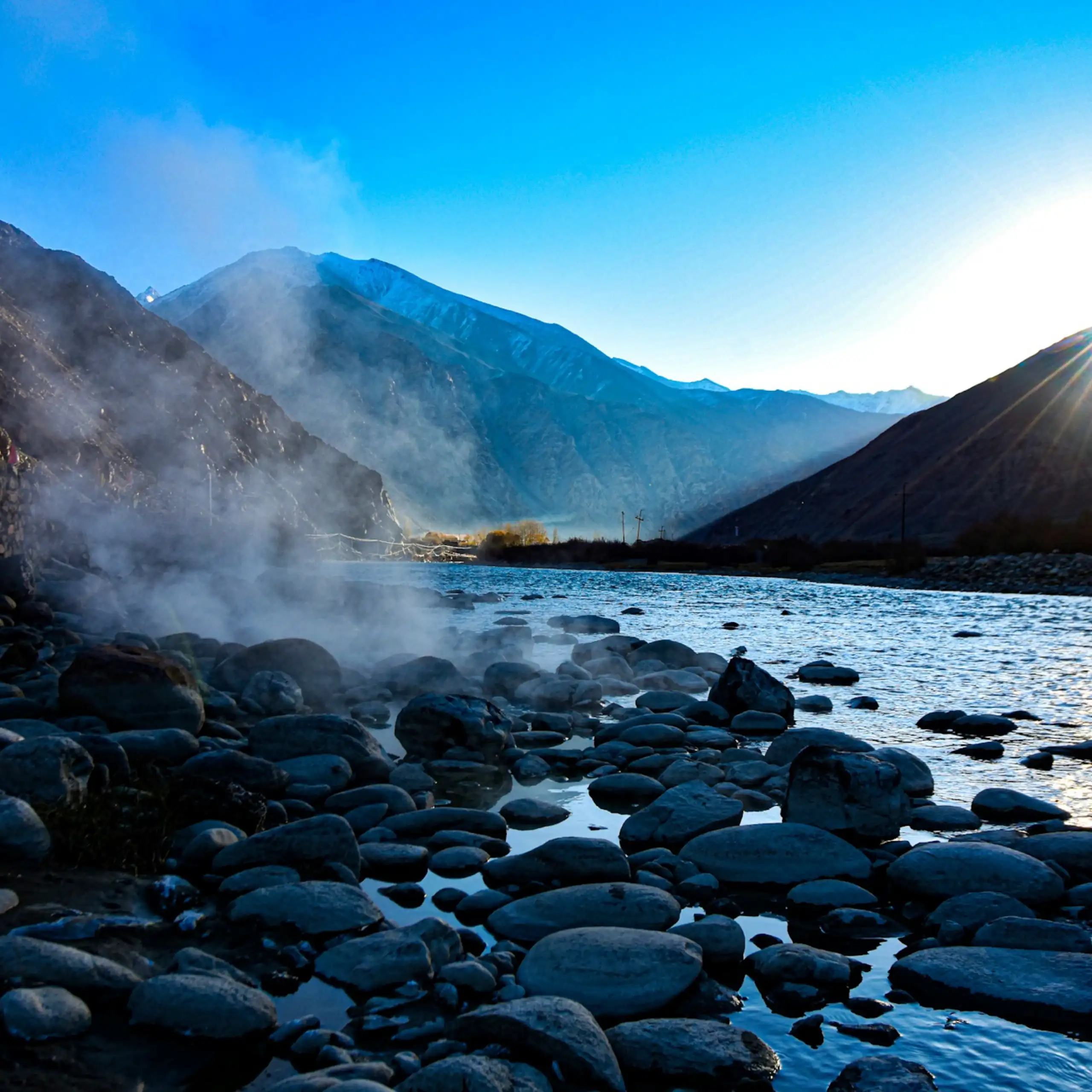 Steam rising from rocky water amid mountains