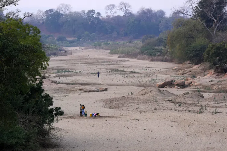 people stand a dried river bed