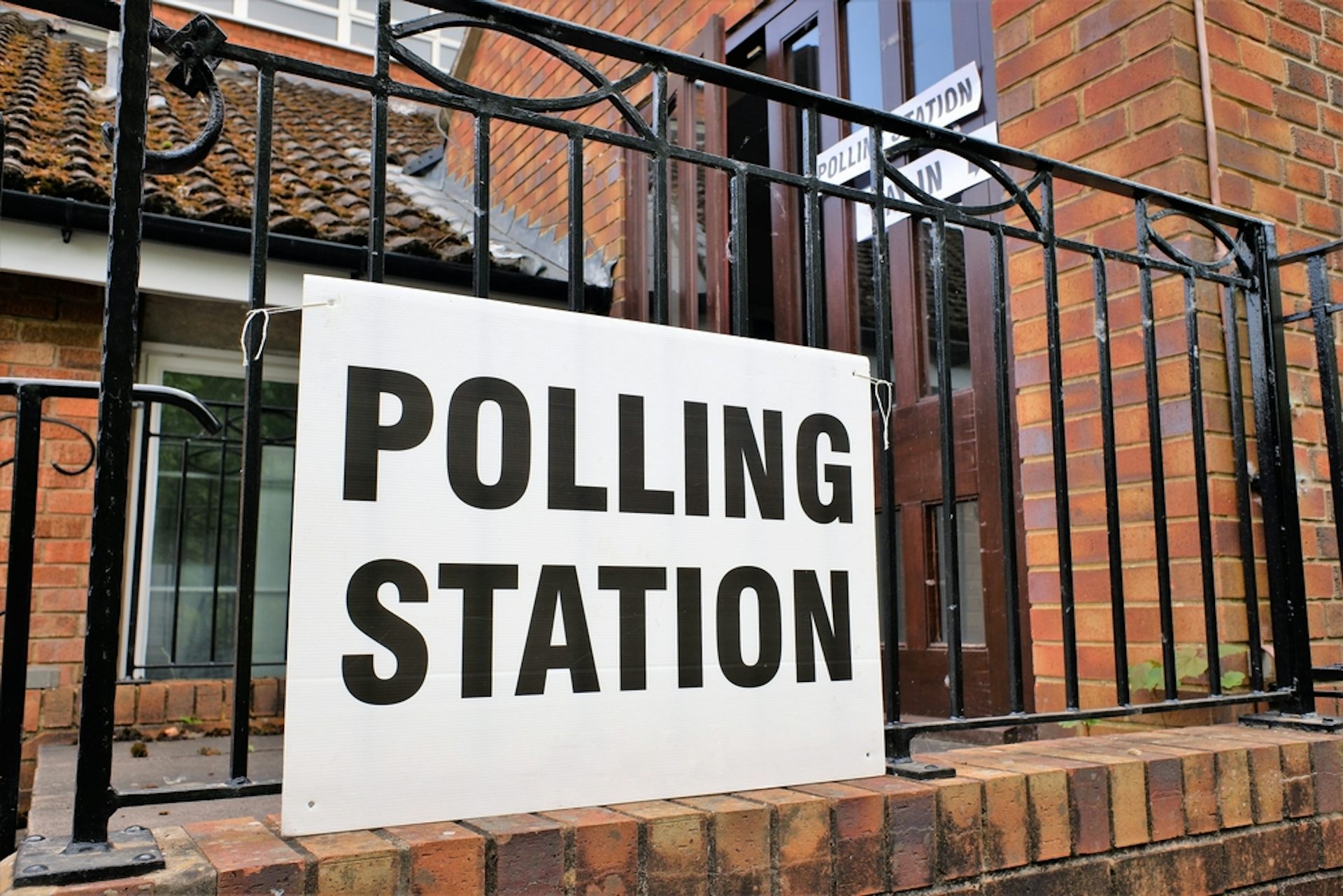 A polling station sign on railings outside church building