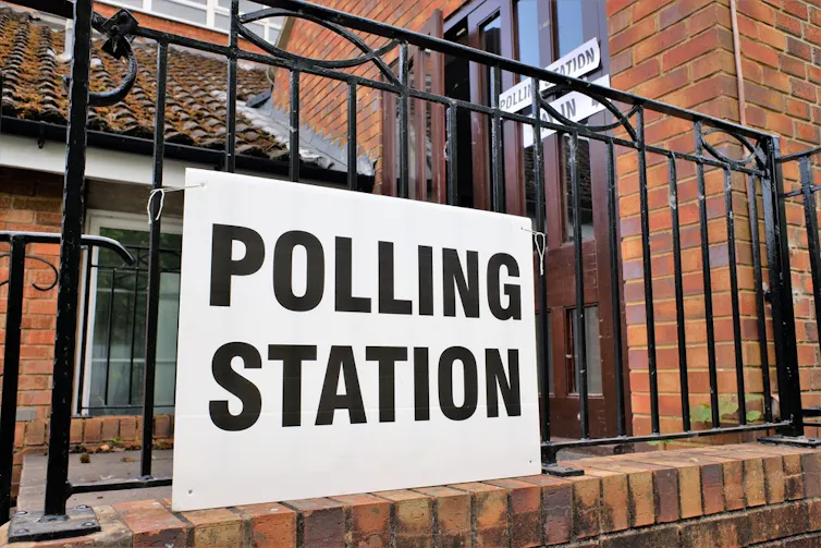 A polling station sign on railings outside church building