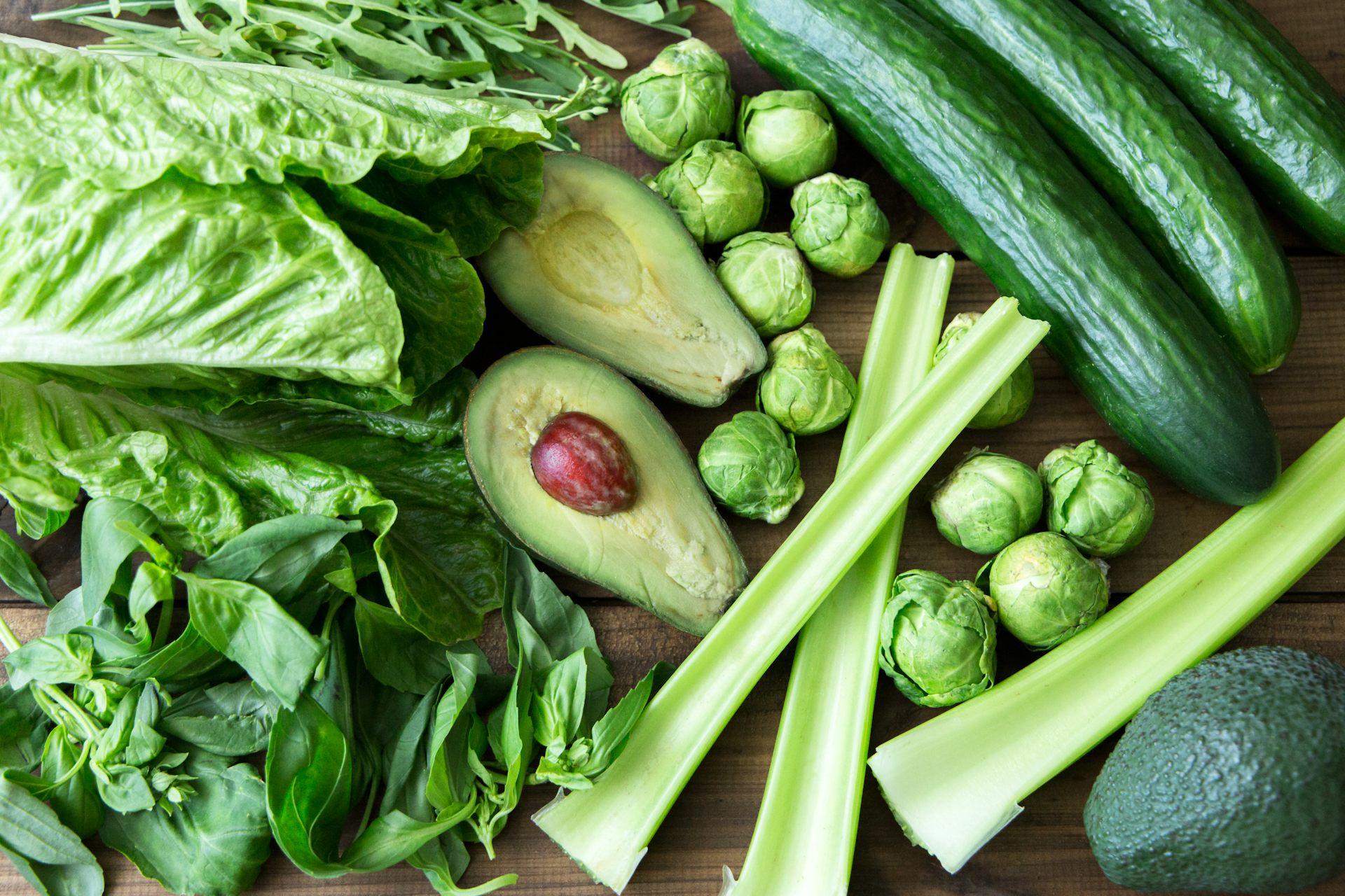 An assortment of foods that are rich in folate, including avocados, cucumbers, celery and lettuce.