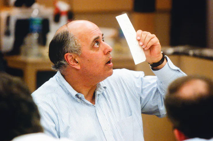 A balding man looking up at a narrow piece of paper.