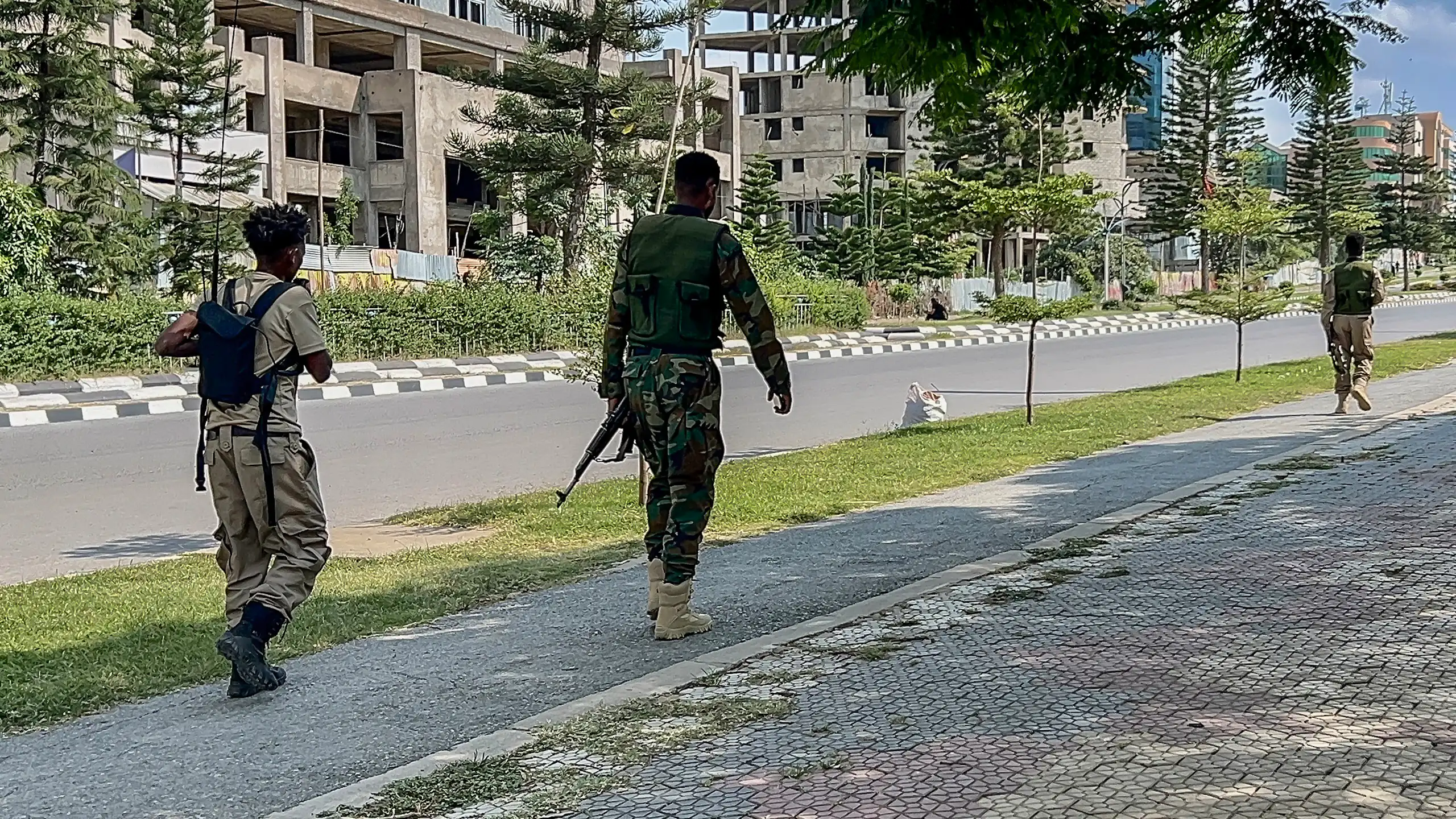 Men in army fatigues walk down the street