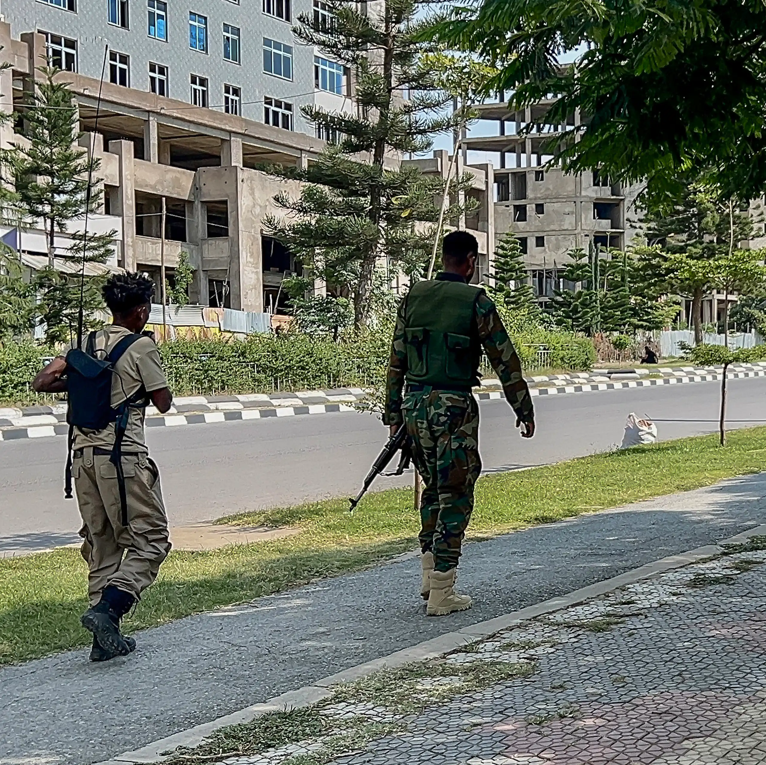 Men in army fatigues walk down the street