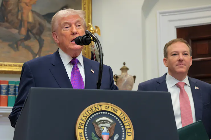 Two men in suits stand at a lectern.