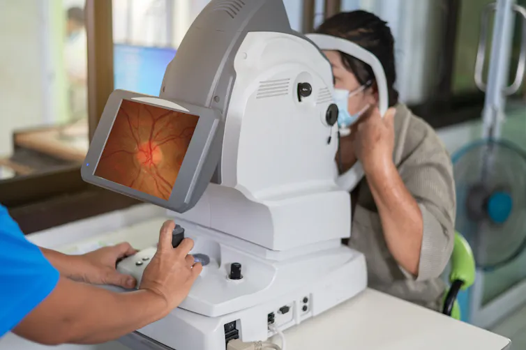 Ophthalmologist takes images of patient's retina using a refractometer eye test machine