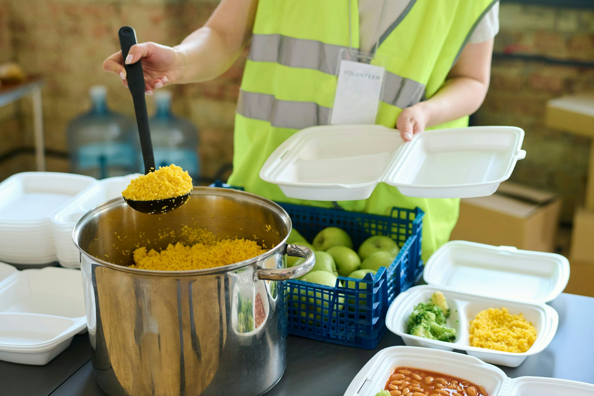Une personne remplit des contenants de repas dans une banque alimentaire.