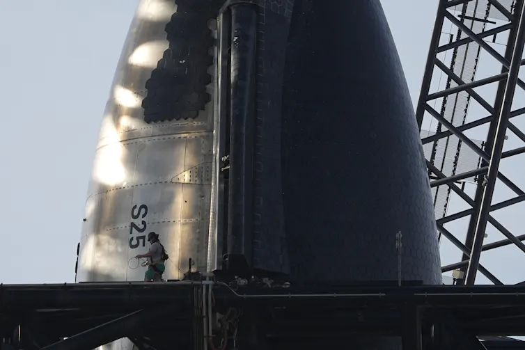 A close of up the tip of the Starship rocket, which looks like a cone, with one side covered in a grid of hexagonal tiles.