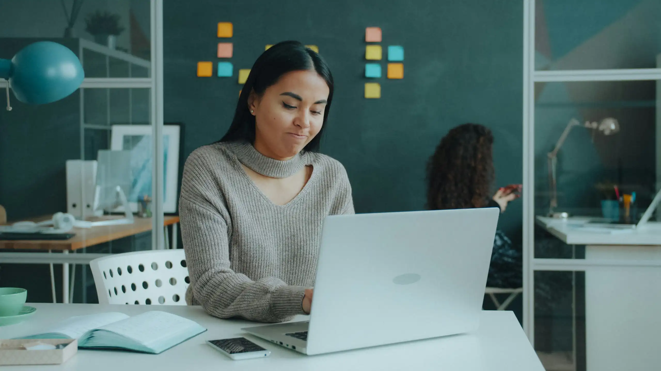 A young woman typing at a computer, with a pensive look on her face