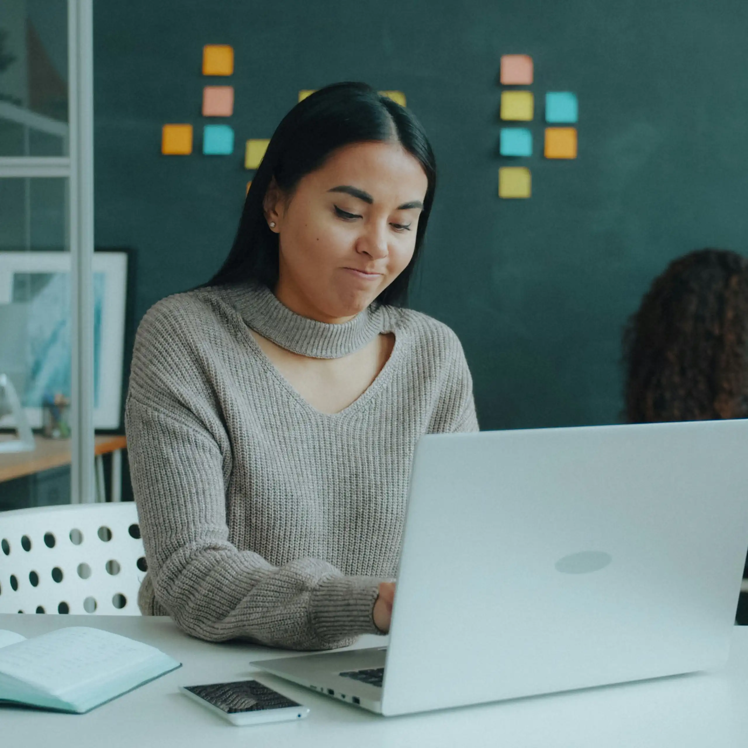 A young woman typing at a computer, with a pensive look on her face