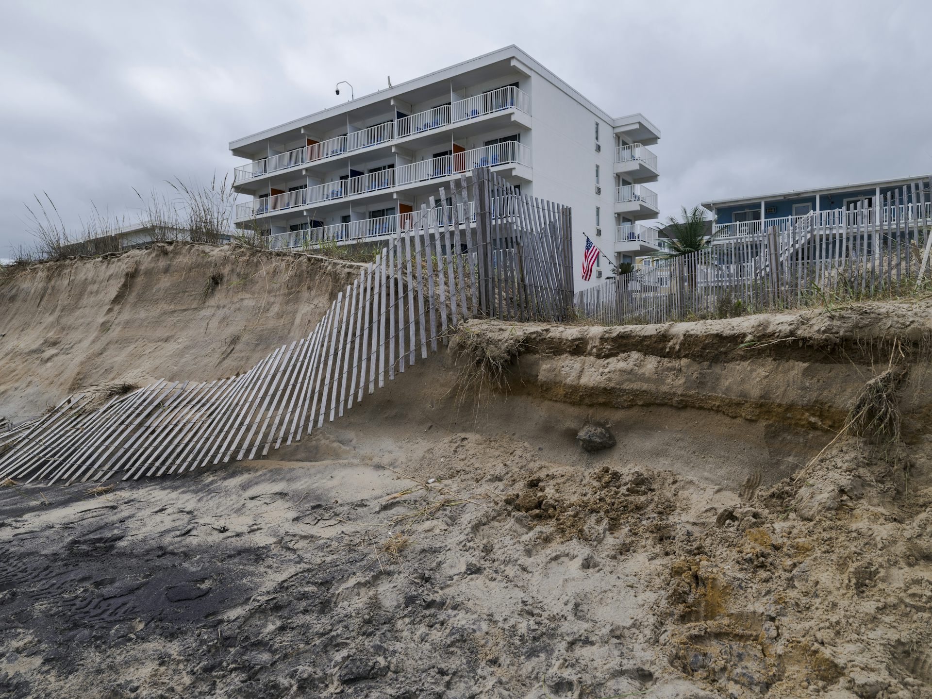 A tall residential building with a partially collapsed and eroded dune.