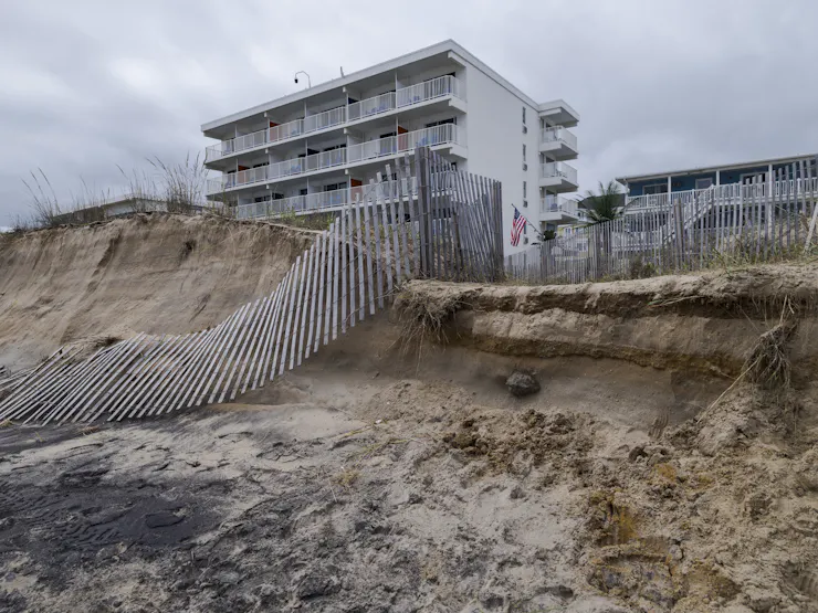 A tall residential building with a partially collapsed and eroded dune.