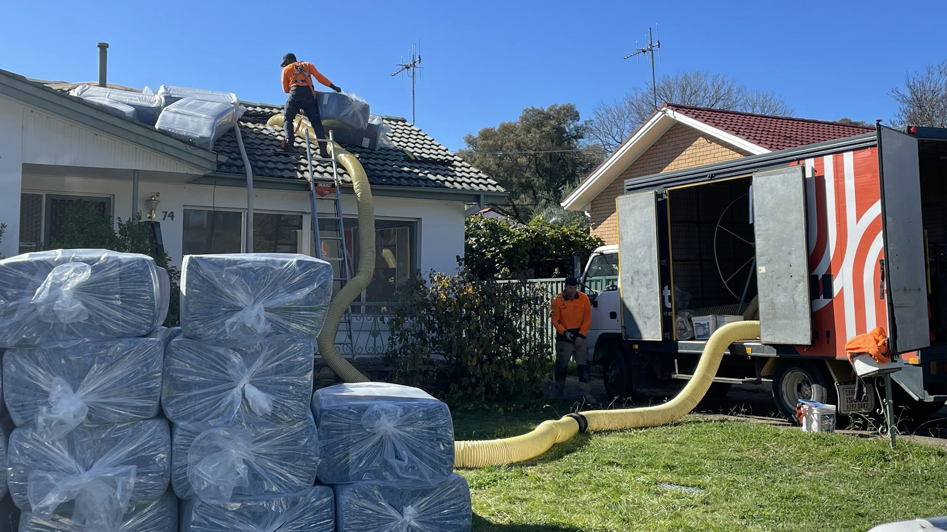 Two men in hi-vis gear work on a house under construction.