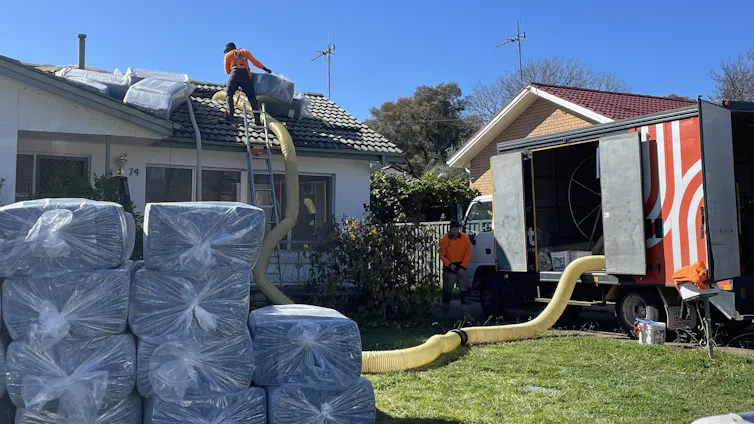 Two men in hi-vis gear work on a house under construction.