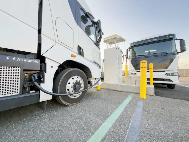 Two electric trucks charging at a commercial EV charging station