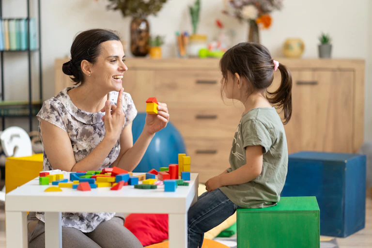 Speech pathologist talks to a young girl.