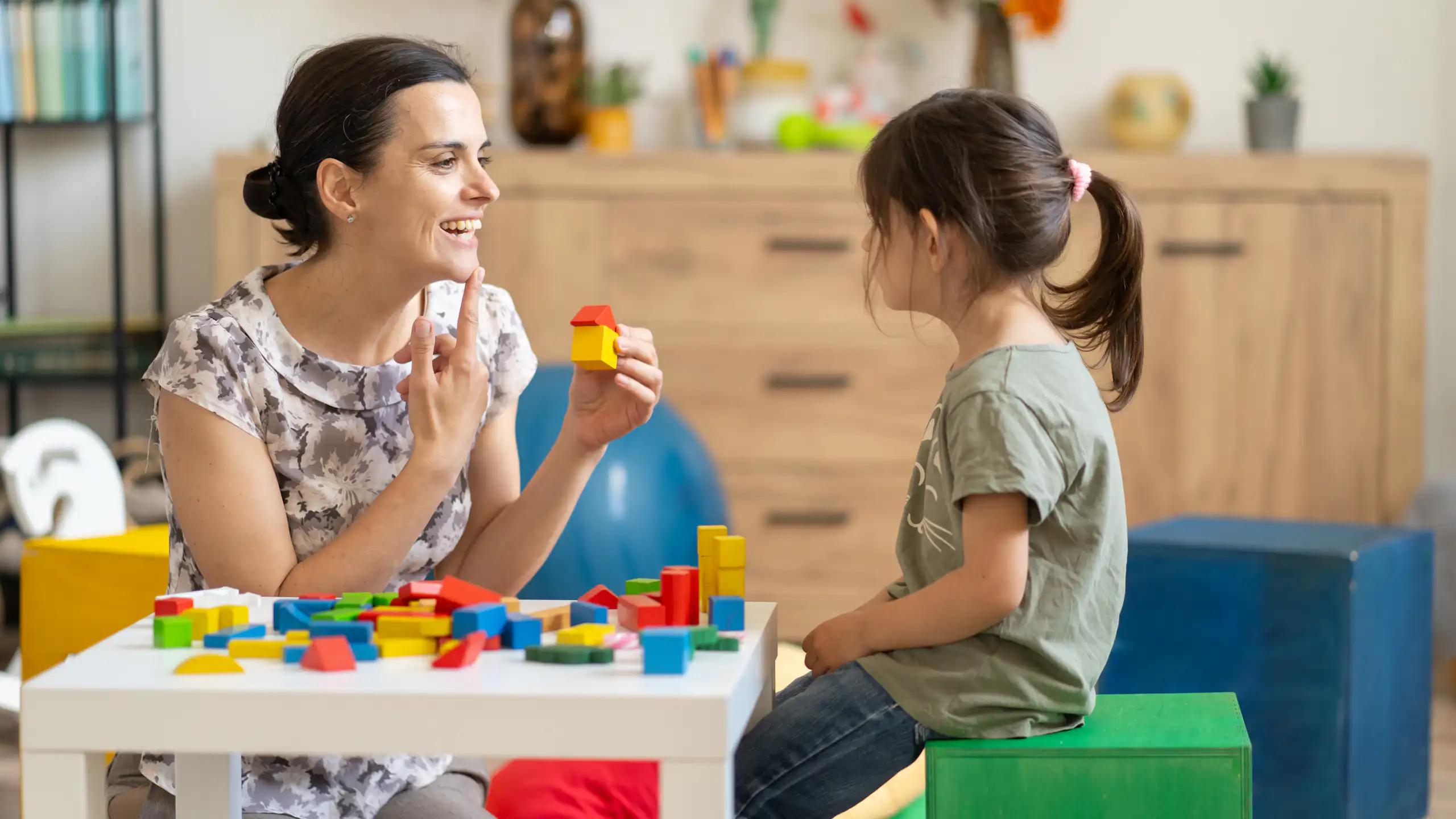 Speech pathologist talks to a young girl.