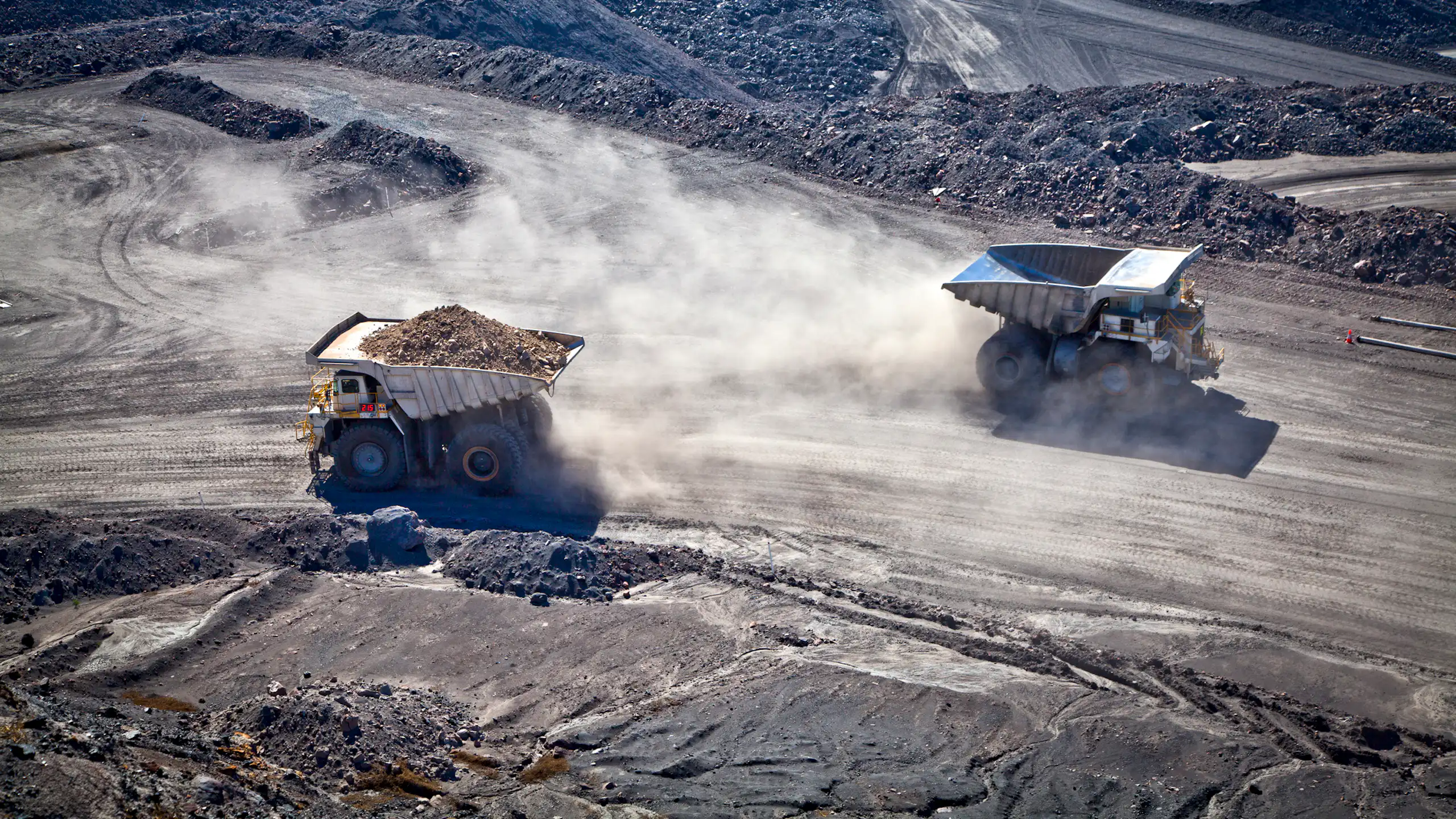 Two trucks haul ore or coal from a mine.