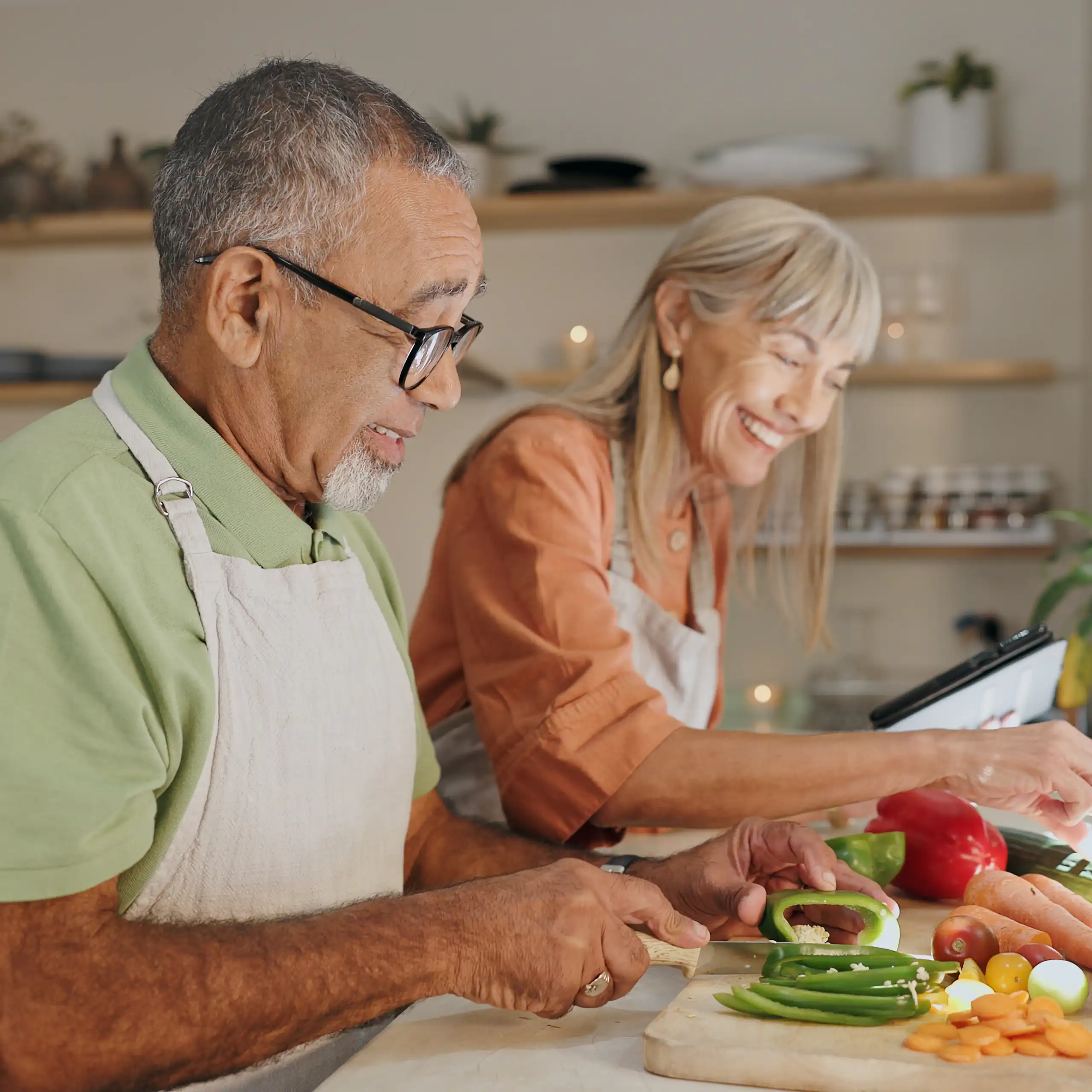 Un hombre y una mujer mayores cocinan juntos sonriendo