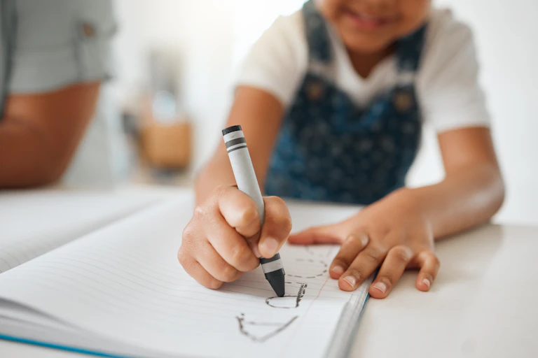 Un niño traza una letra en un cuaderno
