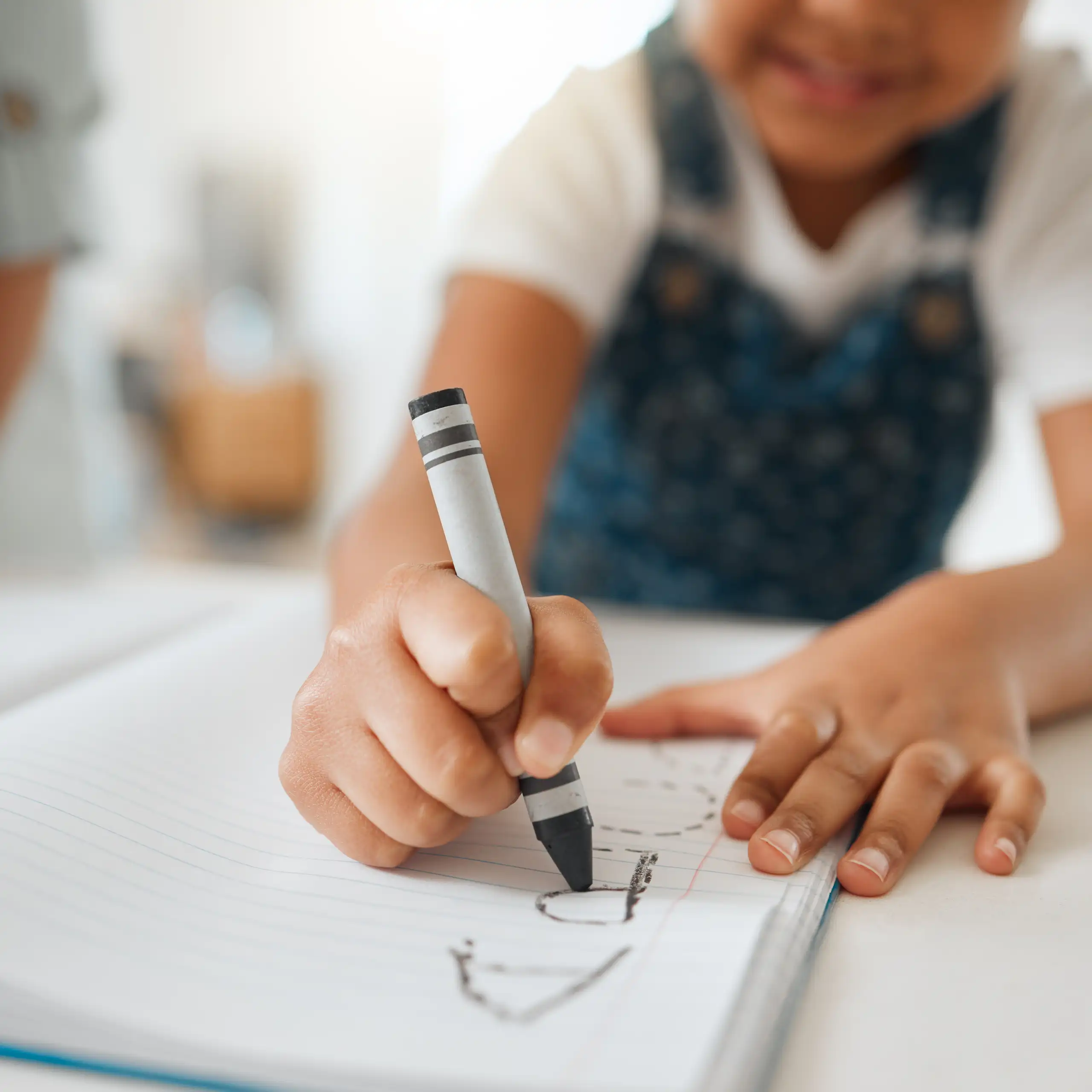 Un niño traza una letra en un cuaderno