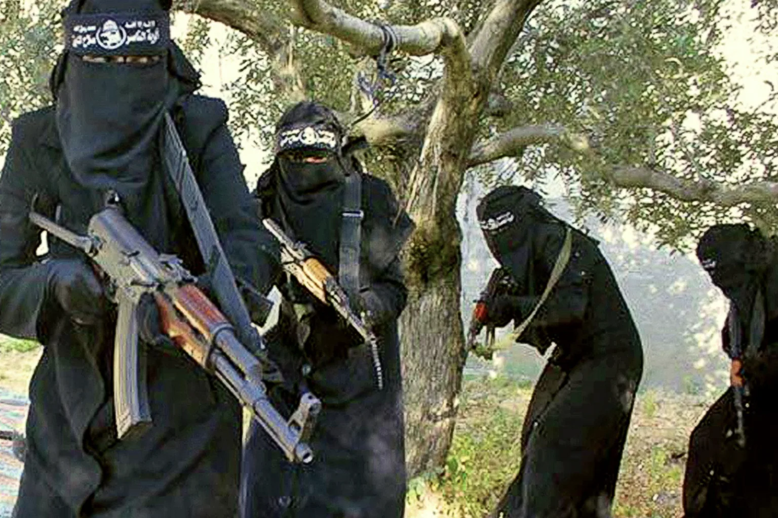 Figures dressed in black burkas carry large guns.