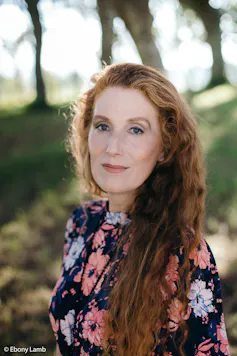 A woman with long red hair and a floral dress