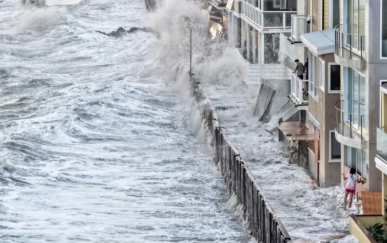 Water laps up against homes along the coast, including inside a temporary barrier created to protect them.