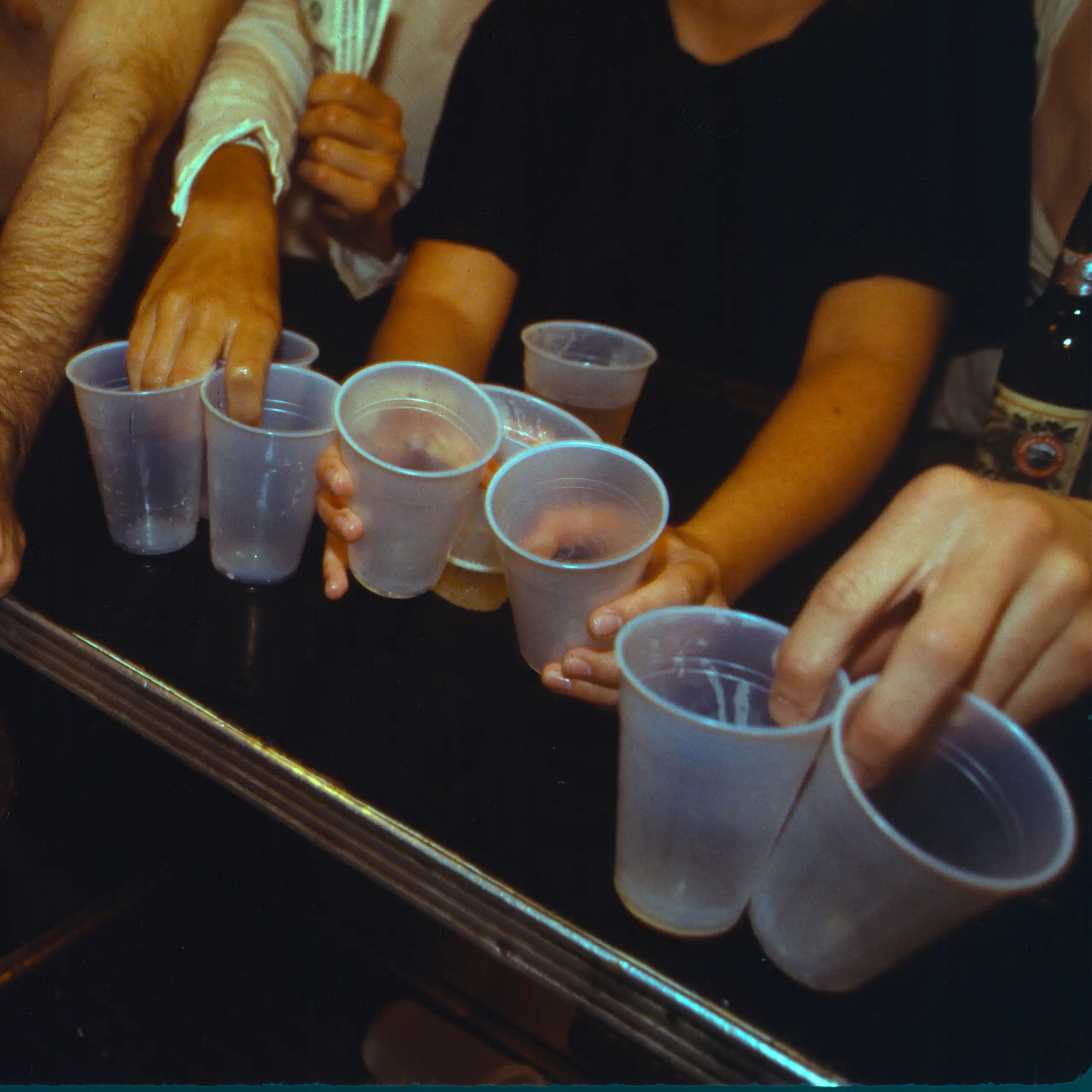 Young men's arms with plastic cups on bar