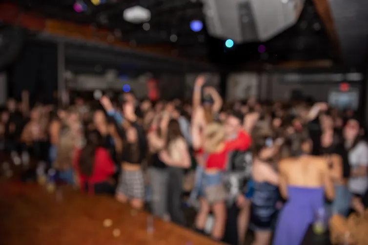 Blurry image of a crowded dancefloor of young adults