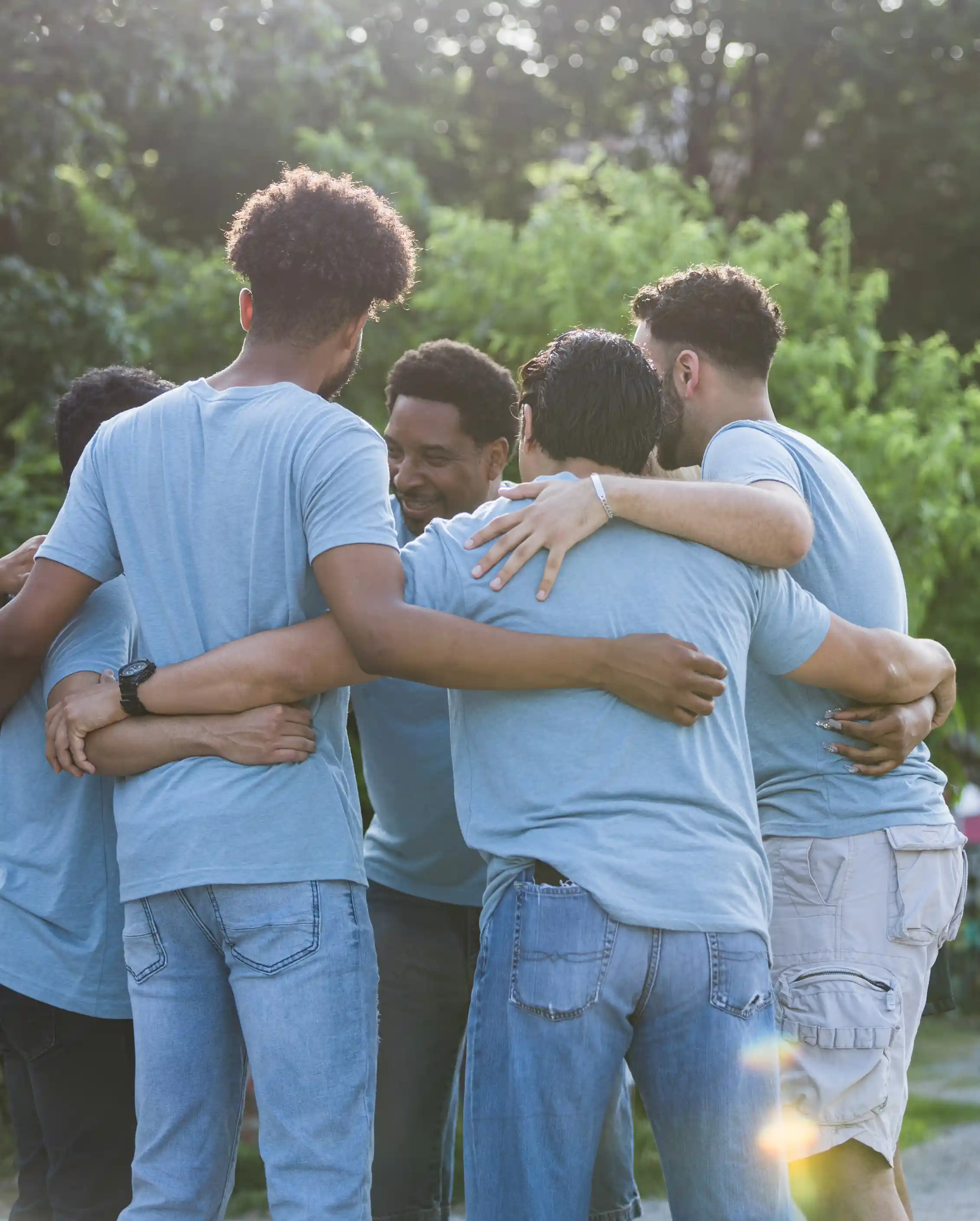 Six young men have their arms around each other in a circle