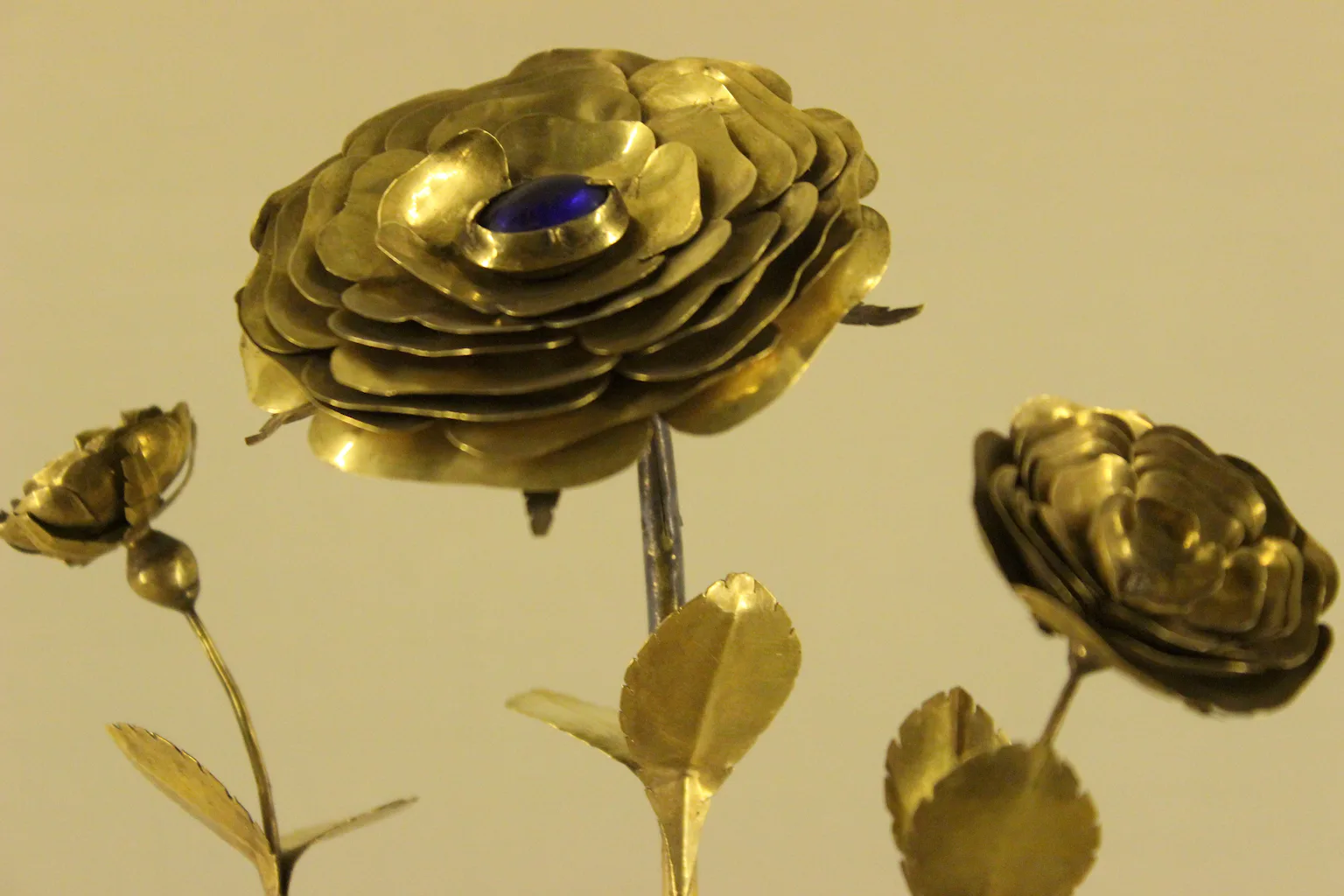 A rose made of gold, with a sapphire set in the center of the flower.