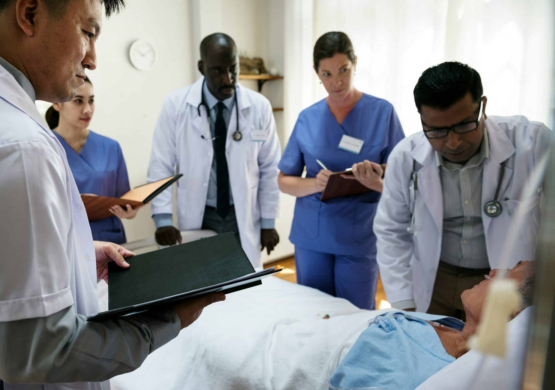 A group of health-care professionals surrounding a patient in a hospital bed