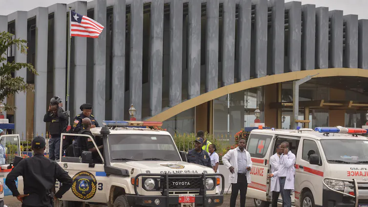 Authorities wait next to vehicles.