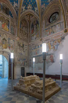 Imagen de dos sepulcros en el centro de la imagen con una capilla repleta de coloridos frescos en la pared.