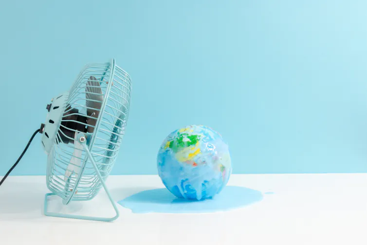 small planet on white desk, big desk fan, pale blue background