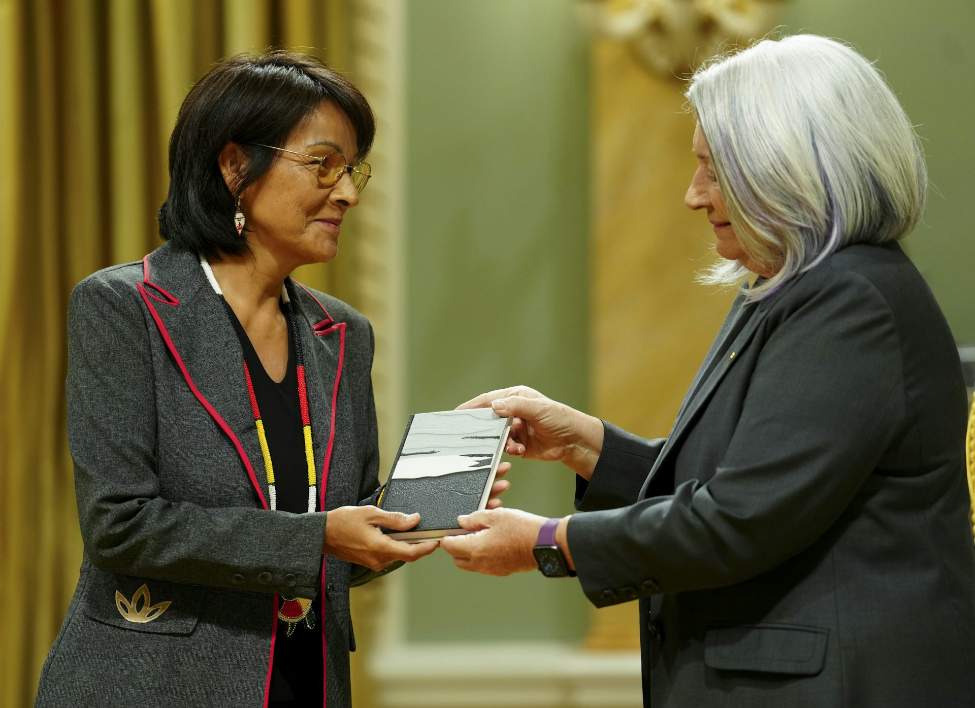 A woman receives an award from another woman.