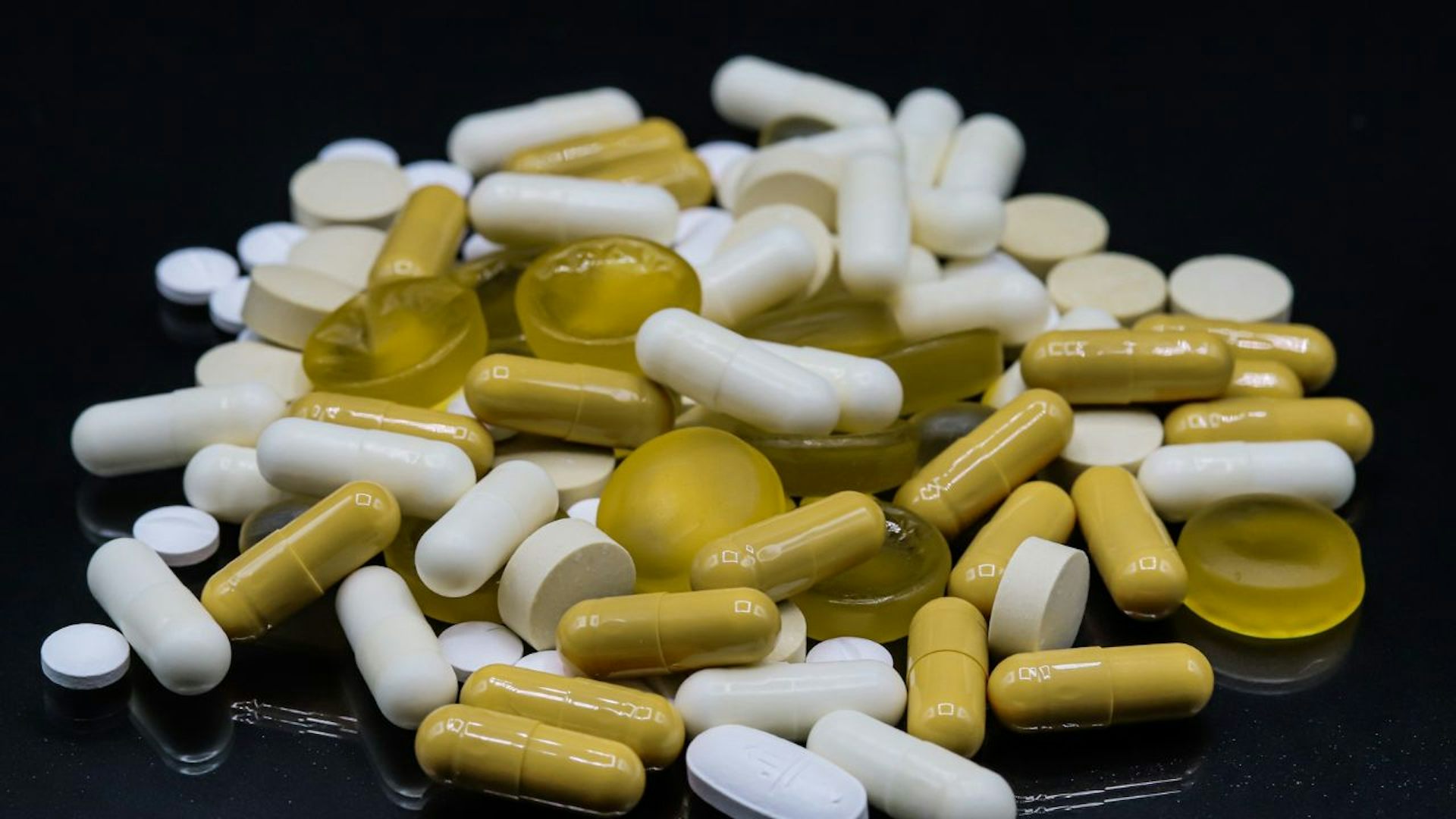 This is a pile of white and green pills on a black background.