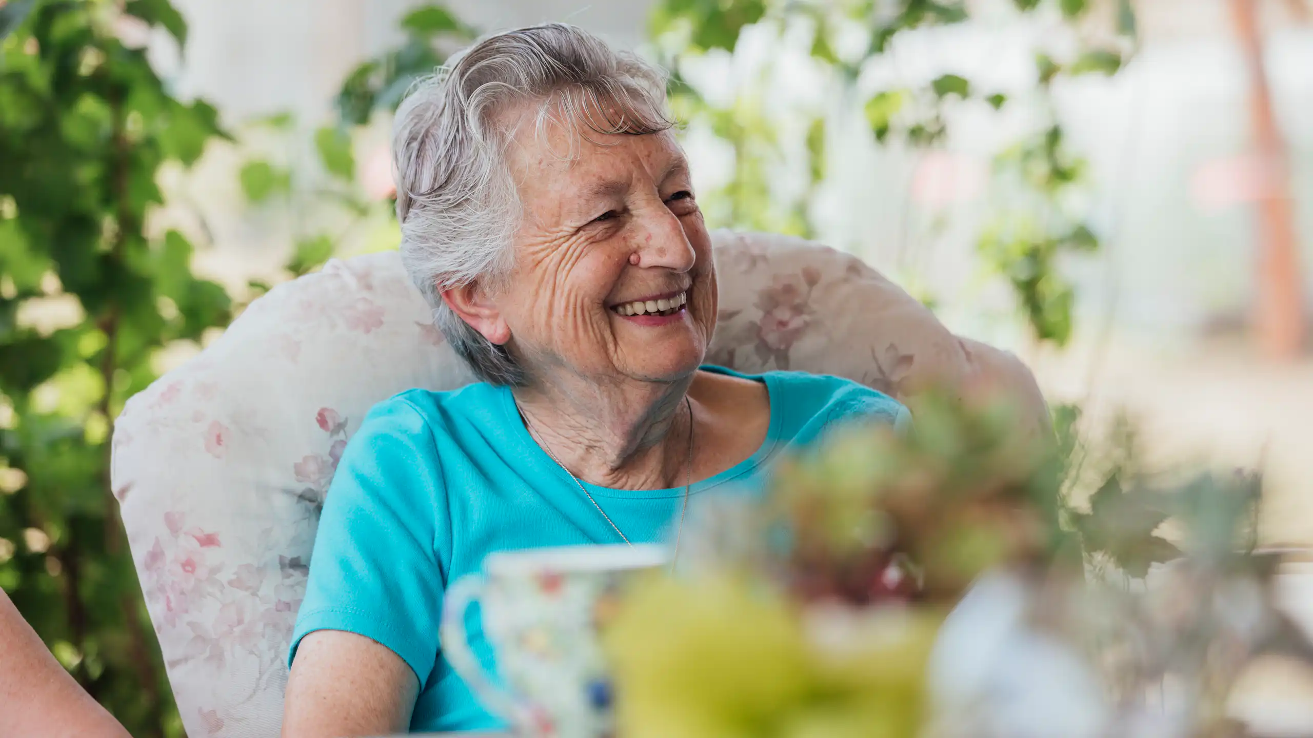 Smiling older woman having a cup of tea outside.