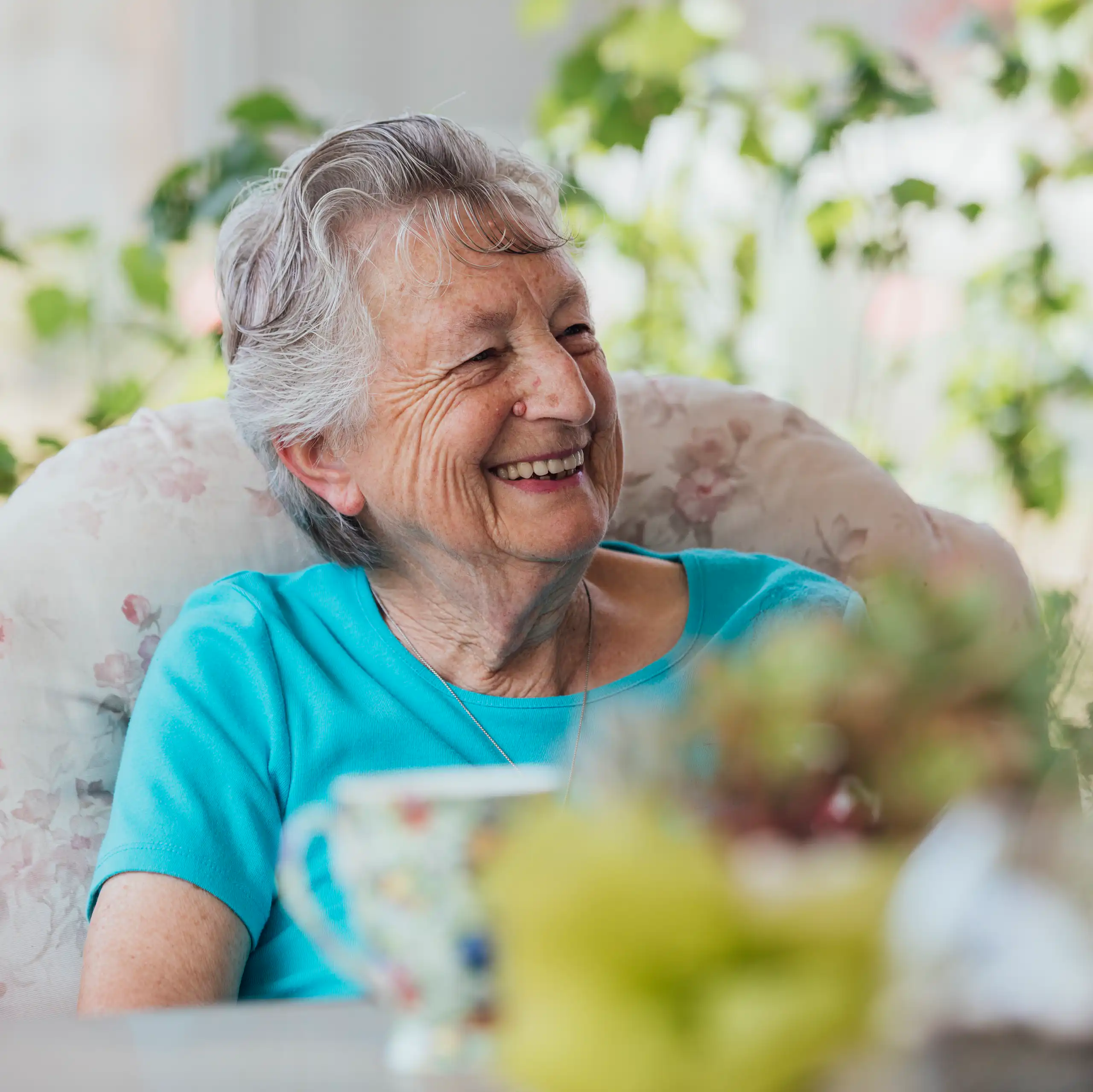 Smiling older woman having a cup of tea outside.
