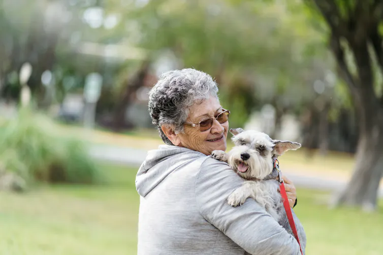 Older adult holding dog in park