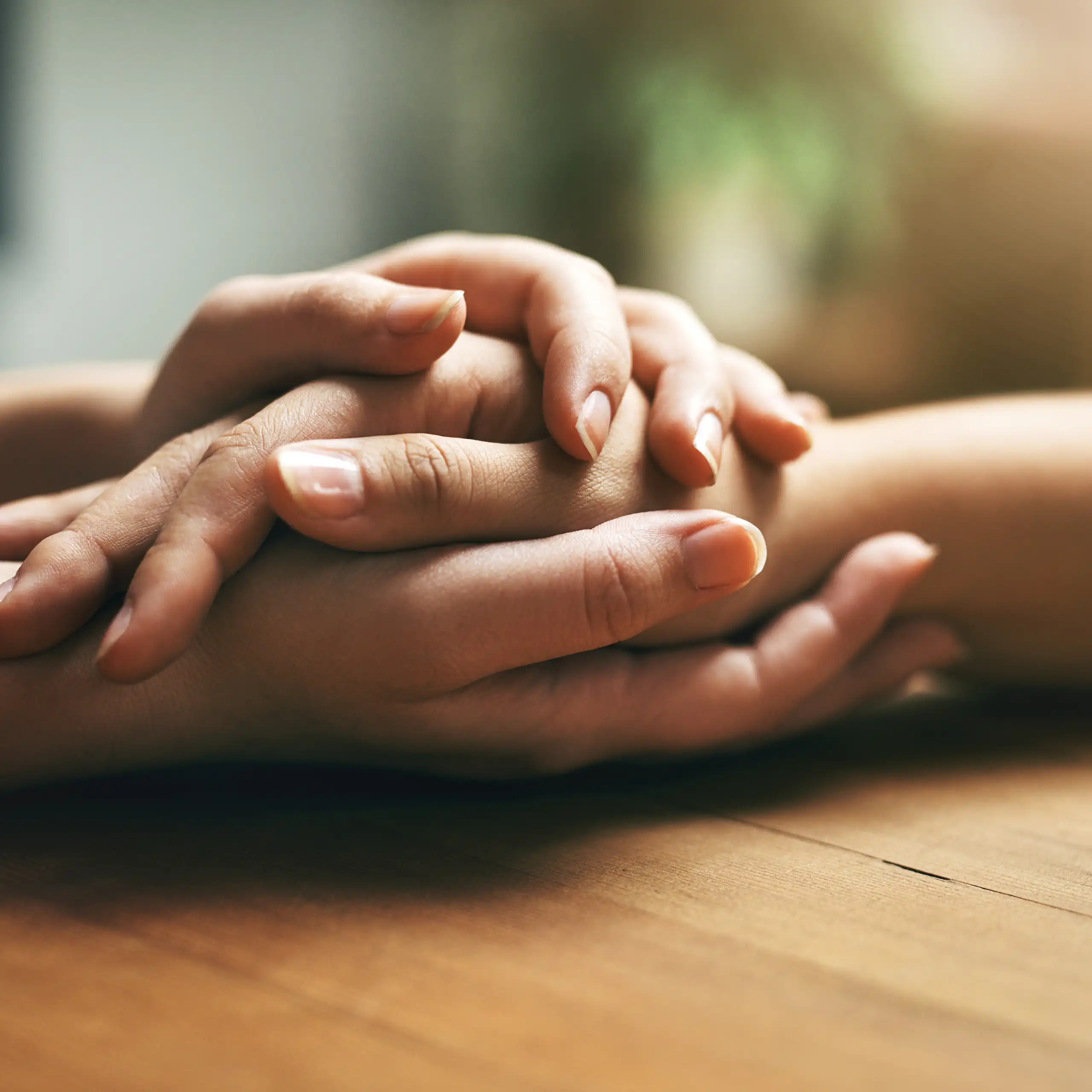 Two sets of hands clasped together over a table
