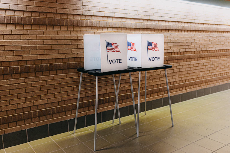 A polling station is seen with two voting booths with American flags and the word 'vote' on them.