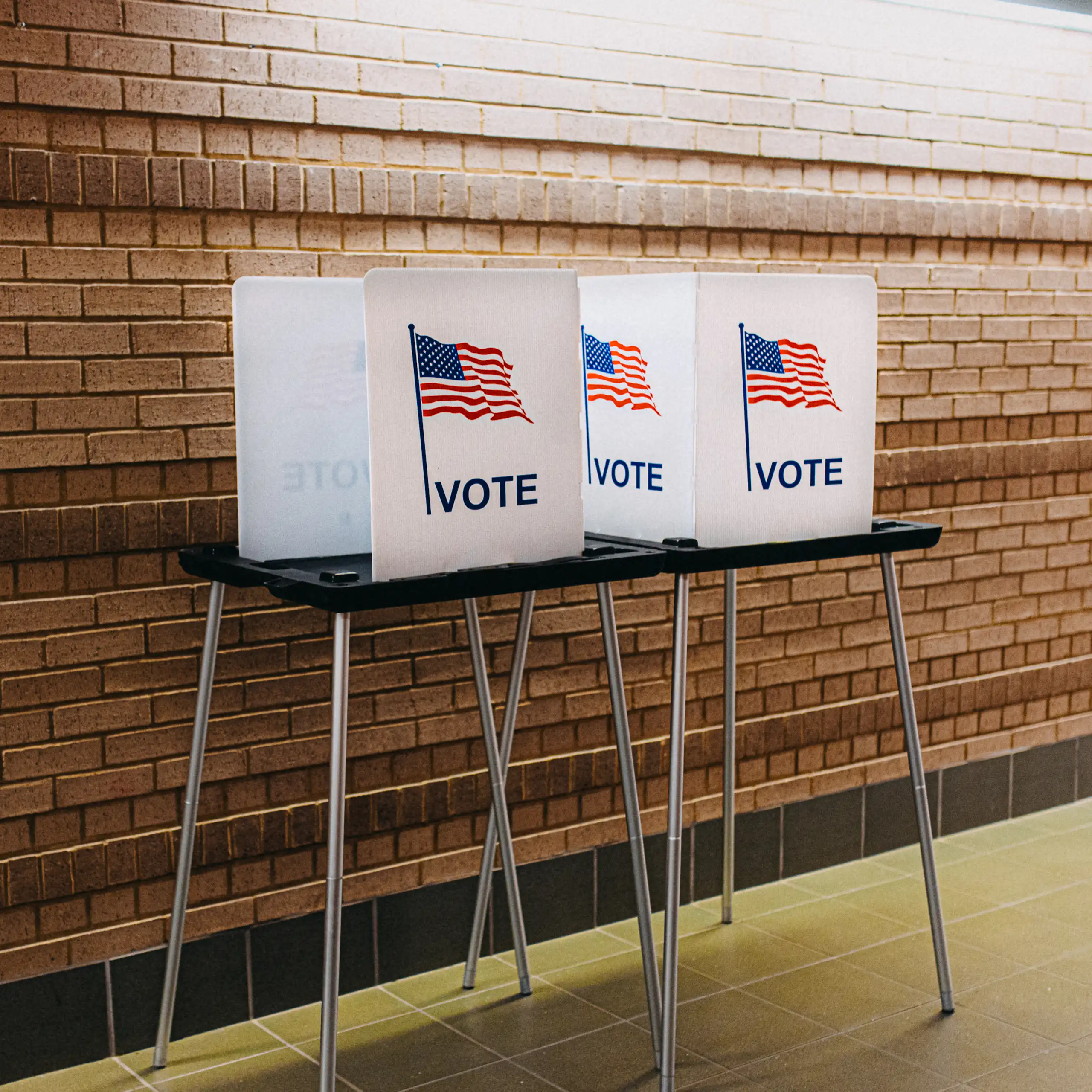 A polling station is seen with two voting booths with American flags and the word 'vote' on them.