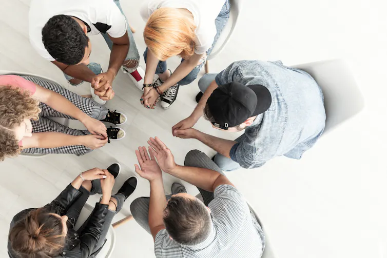 Top view of youth talking with a therapist while sitting in a circle during a meeting.