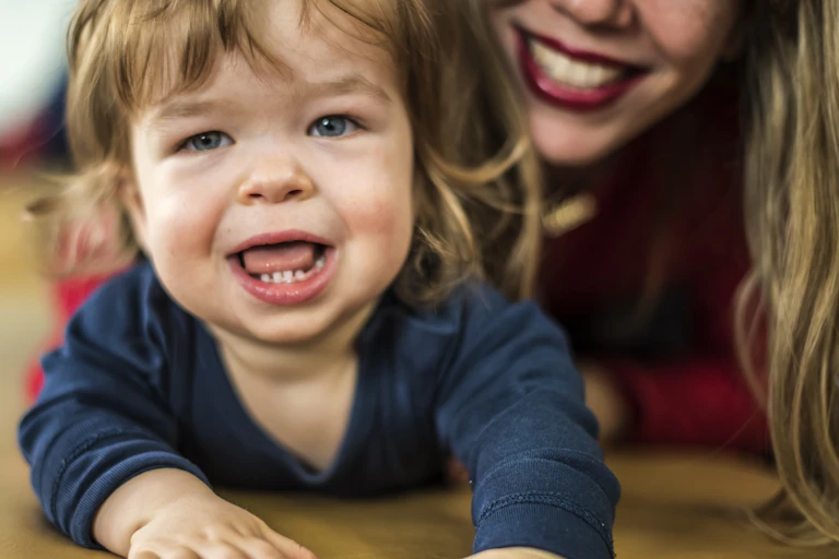 Cropped close up of mum and toddler both smiling into camera