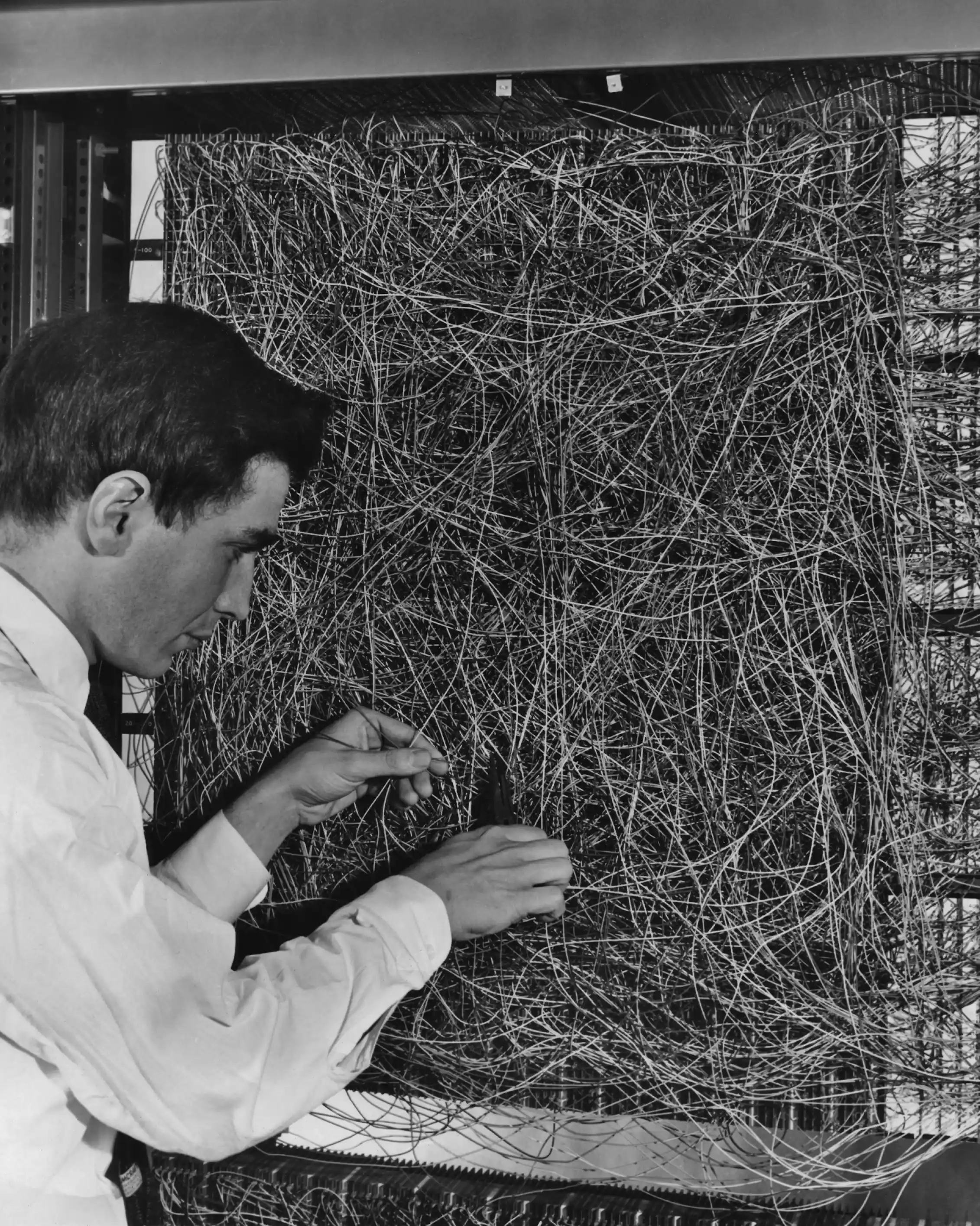 black and white photo of man adjusting a mess of wiring