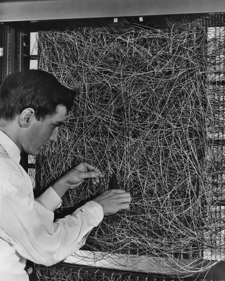 black and white photo of man adjusting a mess of wiring